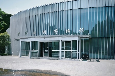 Modern glass facade entrance of Hangzhou Silk Museum surrounded by green trees