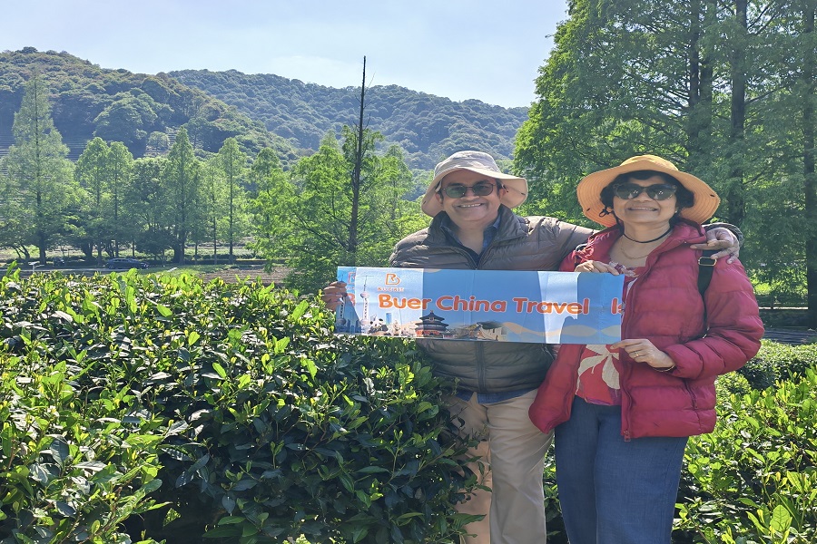 Our lovely foreign guests holding our banner and taking memorable photos among vibrant green Longjing tea terraces in Hangzhou Meijiawu Village
