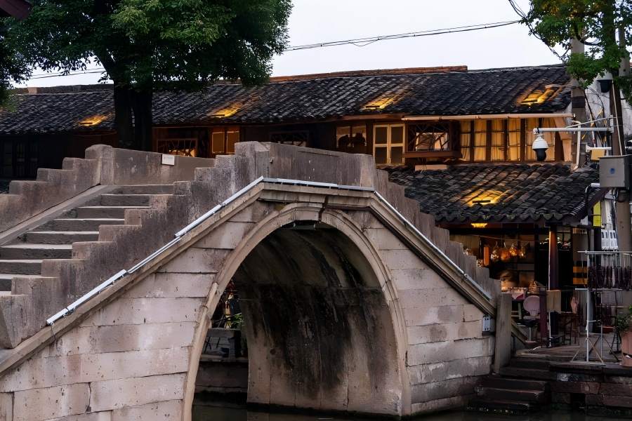 Quiet ink-wash style Jiangnan scenery of Anchang Ancient Town, clear river reflecting white-wall black-tile buildings, drifting black-awning boats and winding covered verandas along waterways
